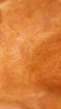 Dikey video. Parıldayan sıvı dalga. Köpüklü boya. Odaklanmamış altın rengi metalik parıldayan kum parçacıkları dokusu mürekkep emülsiyonu sıvı akış hareketi soyut sanat arka planı.