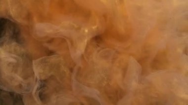 Işıldayan mürekkep suyu. Yüzen buhar. Bulanık sarı altın rengi, parlak parçacıklar, siyah soyut sanat arka planında sis dalgası hareketi..