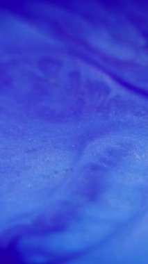 Dikey video. Köpüklü sıvı dalgası. Islak sim dokusu. Odaklanmamış mor renk parlak tahıl parıldayan kum tanecikleri mürekkep rengi boya akış hareketi soyut sanat arkaplanı.