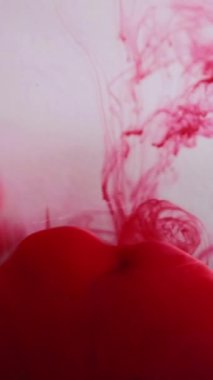 Dikey video. Mürekkep bulutu akışı. Duman boyası. Parlak kırmızı kan rengi su sıvısı bulanık sis dalgası çözünmüş beyaz soyut sanat arka planında.