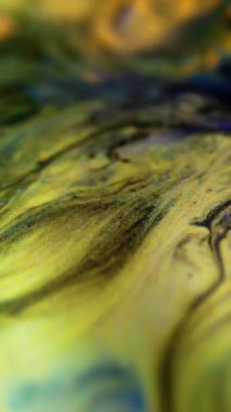 Dikey video. Mürekkep döküldü. Parlak sıvı dalga. Odaklanamayan sarı mavi renk karışım metalik ışıldayan sim parçacıkları boya emülsiyon sızıntısı hareket soyut sanat arkaplanı.