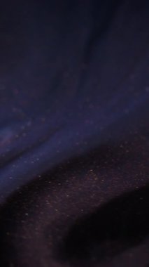 Dikey video. Parlak mürekkep dökülmüş. Boya akışı. Odaklanmamış mor renkli parlak toz parçacıkları pigment sıvı karışımı hareket soyut sanat arka planı.