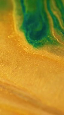 Dikey video. Parıldayan sıvı akışı. Parlak mürekkep karışımı. Odaklanmamış sarı yeşil renk parlak toz zerreleri sıvı boya sızıntısı dalga hareketi soyut sanat arkaplanı.
