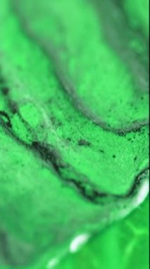 Dikey video. Parlak mürekkep sıvısı. Yağ akışı. Odaklanmamış neon yeşil renk damlası boya emülsiyon parlatıcısı dalga hareket soyut sanat arkaplanı.