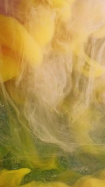 Dikey video. Duman karışımı. Mürekkep akışı. Akışkan sanat. Parlak sarı, mor, beyaz, yeşil, bulut deseni, sıvı, boya, hareket, sis, soyut arkaplan..