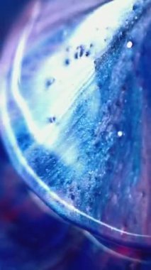 Dikey video. Koni şeklinde. Parlak boya. Odaklanmamış mavi safir parıltısı yansıtılan sabun sıvısı damlası mürekkep parıltısı çok yönlü akış hareketi soyut sanat arkaplanı.