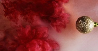 Noel mücevheri. Parlak duman bulutu. Kırmızı pembe mürekkepli parlak altın yuvarlak süs. Suyun karışımı. Yüzen sis dalgası soyut arkaplan..