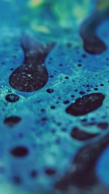 Dikey video. Yağlı köpük dokusu. Boya baloncukları. Odaklanmamış mavi renkli parlak parlak jel damlası mürekkep karışımı dalga hareketi soyut sanat arkaplanı.