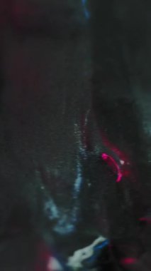 Dikey video. Kimyasal mürekkep. Parlak boya. Odaklanmamış siyah gri renk parlak neon sıvı parlayan metalik emülsiyon floresan parlak sıvı soyut sanat arka planı.