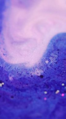 Dikey video. Boya karışımı. Köpük dokusu. Odaklanmamış mavi beyaz renk. Parlak sıvı köpüklerin karışımı. Parıldayan mürekkep lekesi..