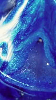 Dikey video. Parlak mürekkep. Parlak değerli taş. Boya akışı. Odaklanamayan mavi renk lüks kristal parlaklık ışık saçan sıvı damlalar ışık akışkan soyut sanat arka planı.