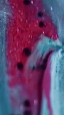 Dikey video. Boya dökülmüş. Parlak sıvı damlası. Odaklanmamış parlak mavi siyah renk parlak pullu partiküller metalik mürekkep akış hareketi soyut sanat arkaplanı.