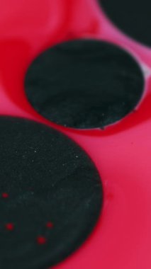 Dikey video. Boya damlaları. Mürekkep akışı. Odaklanmamış mercan pembesi parlak leke emme parlak sıvı yağ damlaları pürüzsüz doku soyut sanat arka planında süzülür.