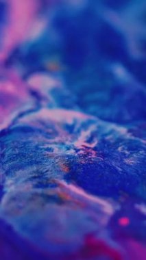 Dikey video. Neon sıvısı sıçraması. Boya karışımı. Odaklanmamış pembe renkli ışıldayan parçacıklar dokusu mürekkep dökülmesi akışı hareketi soyut sanat arkaplanı.