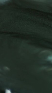 Dikey video. Parlak boya. Metalik mürekkep. Odaklanmamış gri renkli parlak parçacıklar, parlak yağ sıvısı, parlak doku, soyut sanat arkaplanı..