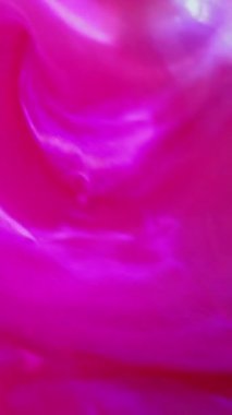 Dikey video. Parlak boya. Neon sıvısı. Odaklanmamış floresan pembe mavi renk ışıldayan parlak sıvı partiküller pürüzsüz doku soyut sanat arka planı.