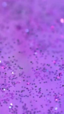 Dikey video. Pırıltılı disko. Neon mürekkebi. Göz kırp. Odaklanmamış pembe mor renkli parlak parlak parlak boya kutlama pulları girdaplı bokeh soyut sanat arka planı.