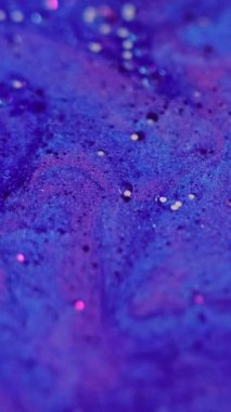 Dikey video. Kabarcık boyası. Islak mürekkep. Parıldayan su. Odaklanmamış mavi, mor, köpüklü, köpüklü, sıvı, değişken, parlak yağ damlaları. Yıldız, soyut sanat arka planında süzülüyor..
