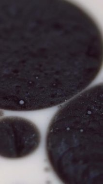 Dikey video. Boya lekeleri. Mürekkep yağı. Odaklanamayan siyah beyaz renk koyu lekeler sıvı füzyon ışıltılı noktalar yüzen ıslak doku hareketi soyut sanat arkaplan.