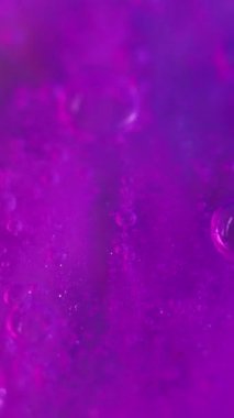 Dikey video. Neon boya. Su kabarcıkları sıvıdır. Disko ışığı. Odaklanmamış yanardöner mor renk gradyan parıltı sıvısı köpük mürekkep hareketi soyut sanat arkaplanı.