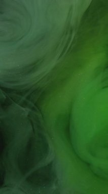 Dikey video. Duman girdabı. Boya suyu karışımı. Odaklanmamış neon yeşili parıltılı toz parçacıkları buhar yüzüyor hareket eden soyut sanat arkaplanı yayıyor.