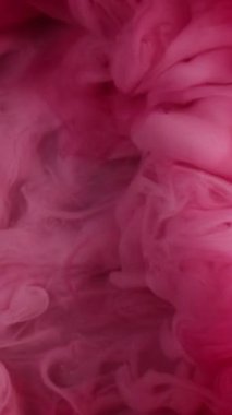 Dikey video. Boya suyu sıçraması. Buhar bulutu. Odaklanmamış pembe renk parıldayan parçacıklar patlama dumanı soyut sanat arkaplanı.