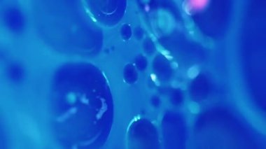 Dikey video. Serum köpükleri. Yağ sıvısı. Odaklanmamış mavi renk şeffaf boyalı su damlacıkları yüzen doku hareketli soyut sanat arkaplanı.