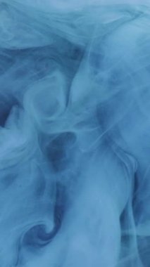 Dikey video. Işıltılı sis girdabı. Suyu boya. Odaklanamayan mavi renk parıldayan toz parçacıkları dokusu koyu soyut sanat arka planında parlayan duman akışı.