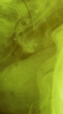 Dikey video. Boya su sıçratır. Sis bulutu. Odaklanmamış sarı neon rengi parlayan ipek buhar dokusu mürekkebi girdap gibi soyut sanat arkaplanı.