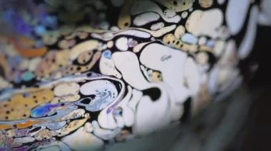 Psikedelik boya. Benzin yağı. Odaklanmamış sarı pembe renkli gökkuşağı damlacıkları koyu siyah soyut sanat arka planında kaygan bir hareket harmanlarlar.