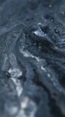 Dikey video. Parlak sıvı dokusu. Mürekkep dalgası. Bulanık gri gümüş rengi parlak metalik toz parçacıkları pigment boya karışımı sıvı akış hareketi soyut sanat arka planı.