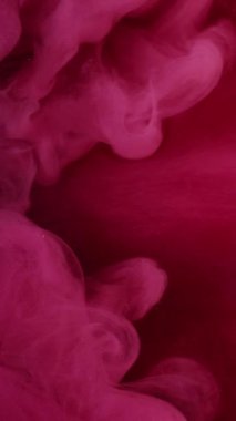 Dikey video. Renkli duman bulutu. Mürekkepli su sıçraması. Odaklanmamış parlak pembe buhar dalgası serbest alan ile hareket soyut sanat arkaplanını ortaya çıkarıyor.