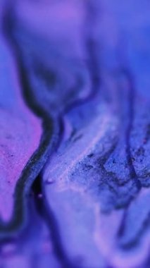 Dikey video. Akışkan sanat. Parlak mürekkep akışı. Bulanık mor renkli parlak taneli tanecikler akrilik boya karışımı sıvı pigment sızıntısı soyut arka plan.