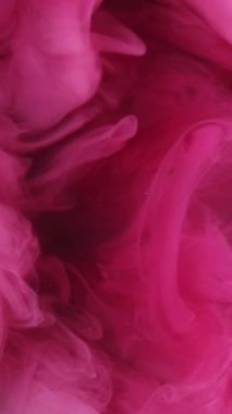 Dikey video. Su damlasını boya. Patlama bulutu. Odaklanmamış pembe renk toz parçacıkları duman dalgası akışı siyah soyut sanat arka planında hareketi ortaya çıkarıyor.