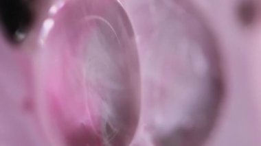 Dikey video. Yağ kabarcıkları. Köpüklü sıvı. Odaksız pembe renk şeffaf yuvarlak damlacıklar yüzen jel dokusu boya su akışı hareketli soyut sanat arka planı.