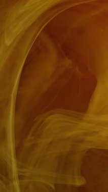 Dikey video. Renkli sis girdabı. Su karışımı boya. Odaklanmamış altın sarısı parlayan buhar dokusu yüzen toz mürekkep döndürme akışı hipnotik hareket soyut sanat arka planı.