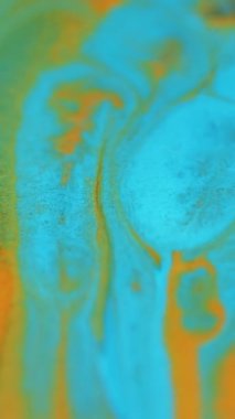 Dikey video. Mürekkep sıçraması. Parlak sıvı karışımı. Bulanık turuncu, mavi, parlak, parlak, parlak kum tanecikleri. Sıvı boya pigmenti, hareket, soyut sanat arkaplanı..