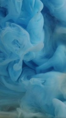 Dikey video. Boya suyu sıçraması. Buhar bulutu. Odaklanamayan mavi beyaz renk parıldayan parçacıklar patlama dumanı soyut sanat arkaplanı.