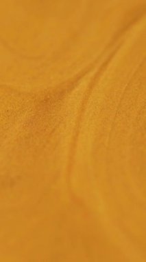 Dikey video. Sıvı sim akışı. Parlak boya dokusu. Bulanık turuncu altın rengi metalik parıldayan kum parçacıkları akrilik sıvı mürekkep sızıntısı soyut sanat arka planı.