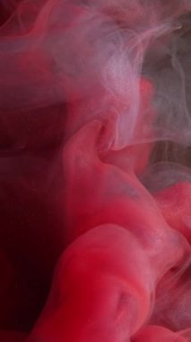 Dikey video. Boya damlası suyu. Renkli duman bulutu. Odaklanmamış kırmızı gri mürekkep karışımı sıçrama hareketi patlama duman dokusu soyut sanat arkaplanı.