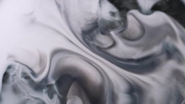 Mürekkep çözülüyor. Grunge akışı. Gri mermer sıvı, beyaz, nemli, soyut arka plan yüzeyine yayılır. Monokrom siyah sızıntıya odaklanmış..
