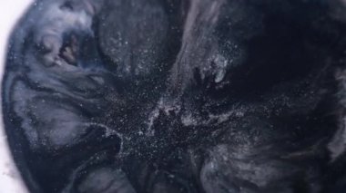 Parlak leke. Mürekkep lekesi. Siyah gri gri sıvı, diş minesi beyaz dokusuna yayılıyor. Lav akışı soyut arkaplan bulanık açıcı efekti.