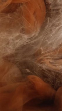 Dikey video. Duman akışı. Sihir. Yüzen mürekkep buharı karışımı. Koyu arkaplan üzerinde turuncu parıltılı sis bulutu hareketi mistik dalga ışıltılı doku sanatı.