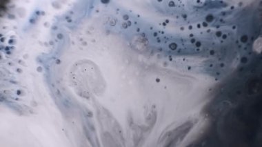 Sanatsal mürekkep. Sıçrama kanaması. Pis beyaz sıvı yüzeyde Grunge damlaları belirir. Gri mavi siyah bulanık ıslak mermer soyut arkaplan.