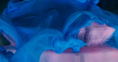 Mistik duman. Hipnoz sıvısı. Pembe mavi kıvrımlı boya cam üzerinde yüzüyor mavi kristal elmas suyun içinde soyut arkaplan çözünmüş.