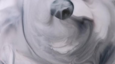 Enamel fırıl fırıl dönüyor. Grunge akıntısı. Gri mermer mürekkep, beyaz, ıslak, soyut arka plan yüzeyine yayılır. Monokrom siyah sızıntıya odaklanmış..