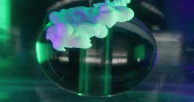 Duman bükme. Cam lens. Yeşil turkuaz mor parlak sıvı boya damlası şeffaf su oval küre figürüne dökülüyor soyut arka plan çözüldü.