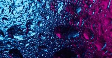 Islak pırıltı. Çok renkli damlalar. Metal folyo parlak yüzeyde yoğunlaştırılmış yağmur akışı. Mavi mor yanardöner soyut bulanık arkaplan.