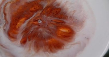 Parıltı patlaması. Boya çiçeği. Turuncu bakır metal toz sıvısı beyaz diş minesi sıvı yüzeyine yayılmış. Yuvarlak lekeler, soyut sanat geçmişi..