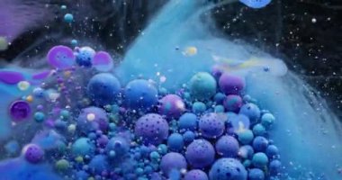 Renkli akış. Kabarcık boyası. Su yağı karışımı pigment damlası patlıyor. Mavi mor parçacıkları dolduran dalga koyu soyut arkaplan.